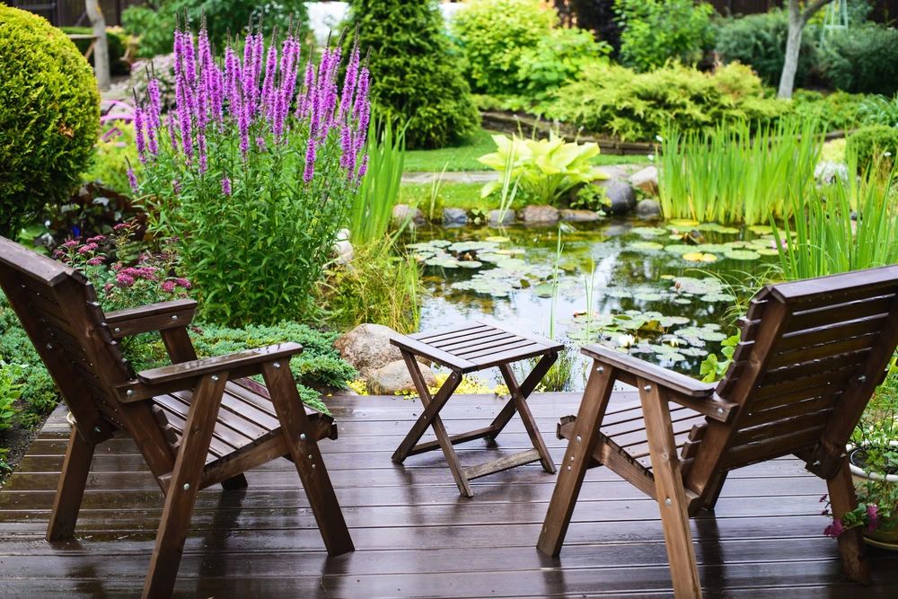 Terrasse en bois avec salon de jardin face à un bassin aquatique aménagé
