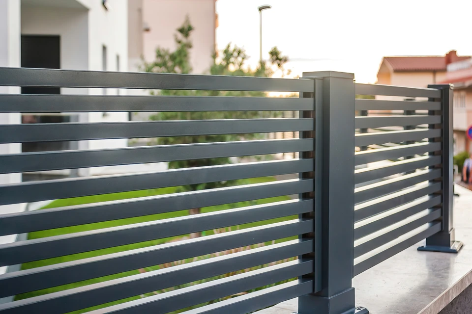 Clôture résidentielle extérieure avec palissade blanche en PVC ou bois peint, montée sur muret en béton avec chaperon brique