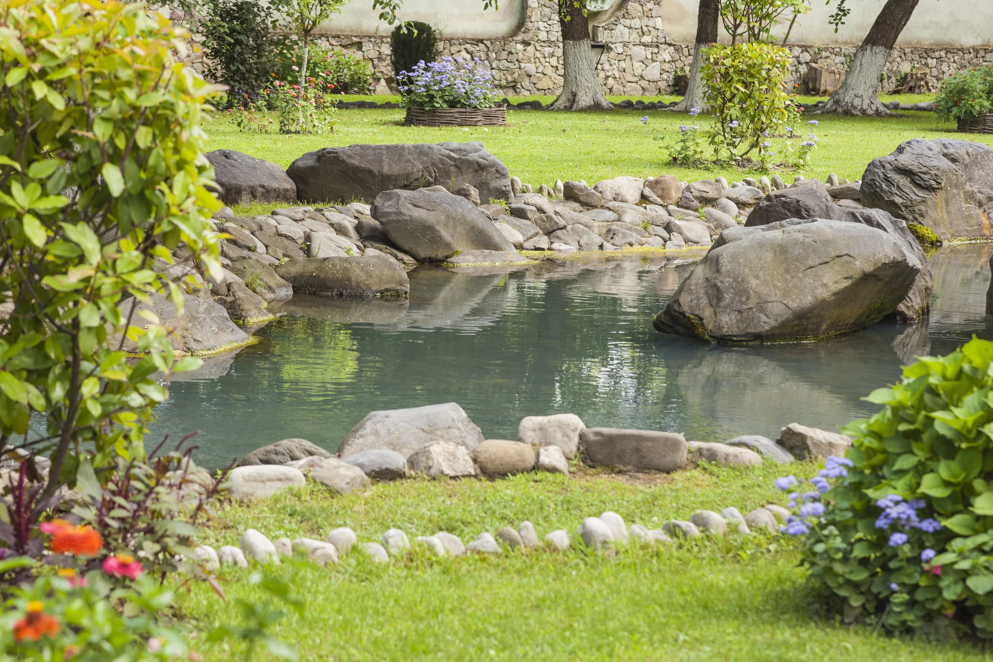 Jardin aquatique extérieur avec cascade artificielle intégrée dans un mur de pierre